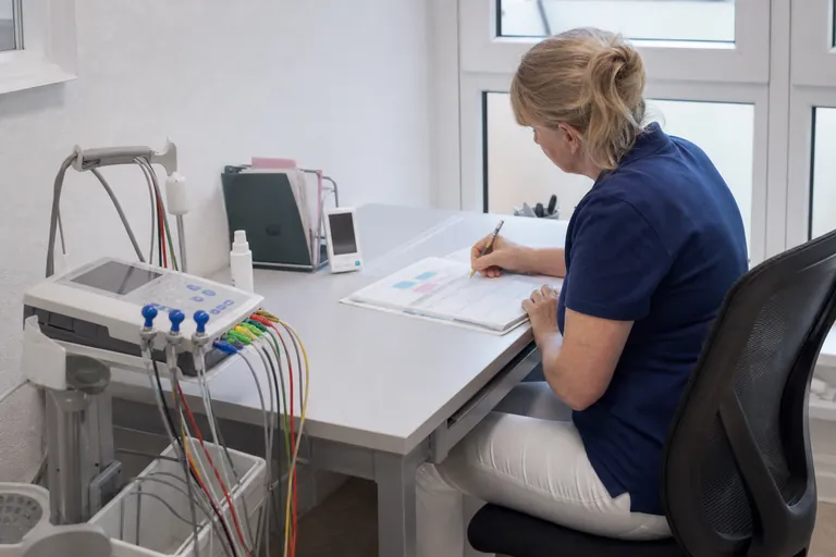 Praxismanagerin plant Prüftermine für ein EKG Gerät in einem digitalen Kalender